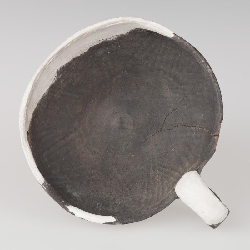 Czerpak o wklęsłym dnie, półkolistym brzuścu, brzegu zaokrąglonym do środka. Wnętrze zdobione odciskiem koła i skośnymi rowkami