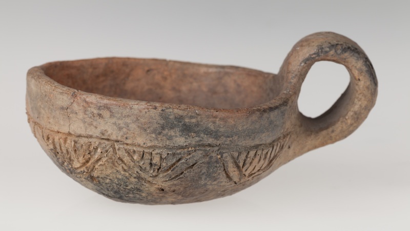 Czerpak półkulisty z wklęsłym dnem, zdobiony dookolnym rytym rowkiem i zwężającymi się trójkątami