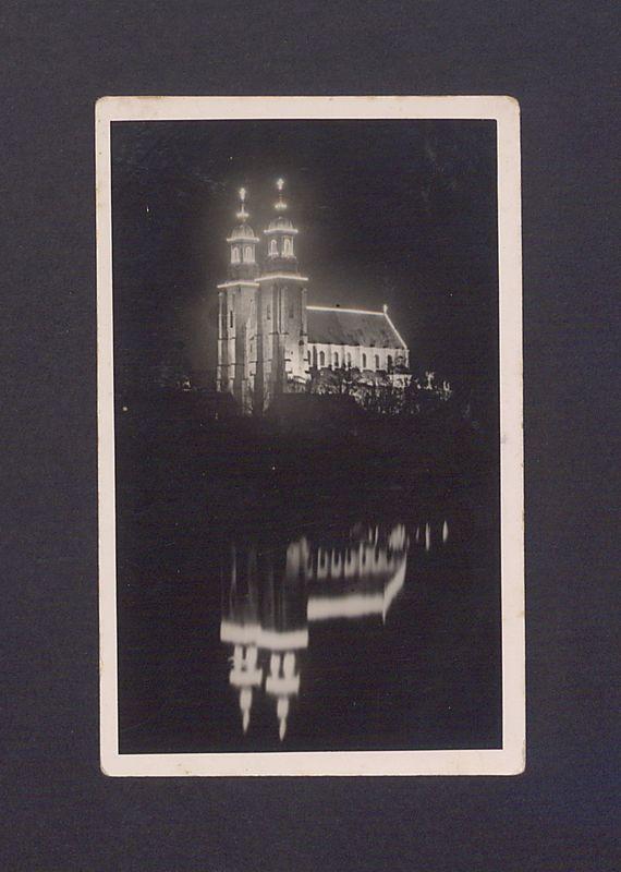 Widok na odświętnie iluminowaną bazylikę. Odbicie katedry w lustrze jeziora Jelonek.