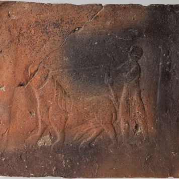 Płytka przedstawiająca mężczyznę trzymającego lwa na arkanie