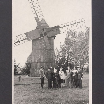 Siedmioosobowa grupa na tle wiatraka na Lednicy.