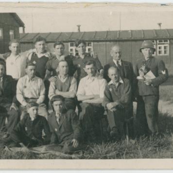 Fotografia grupy mężczyzn przed barakami